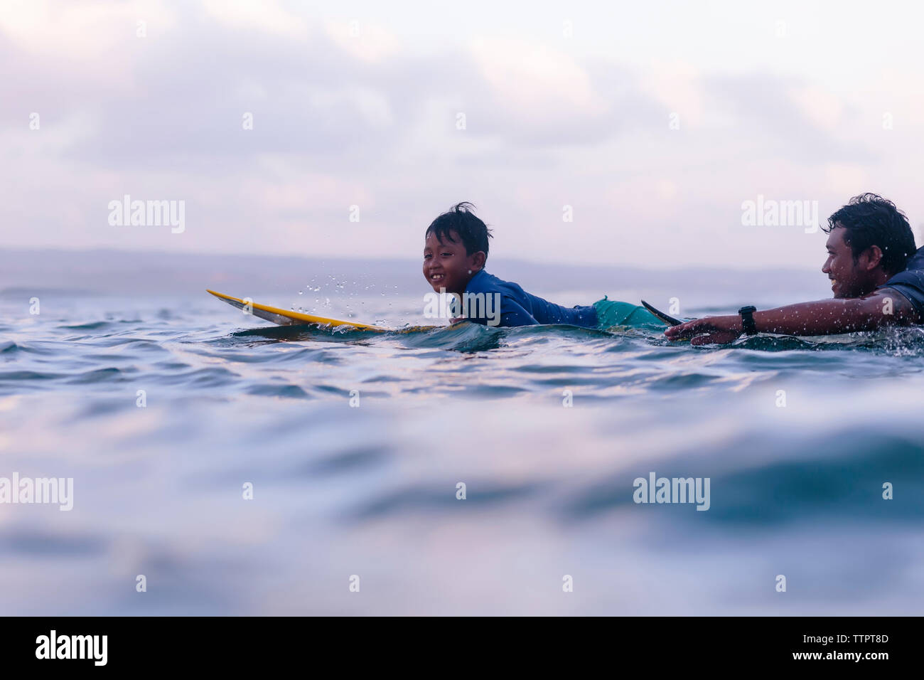 Père et fils du surf en mer contre sky Banque D'Images