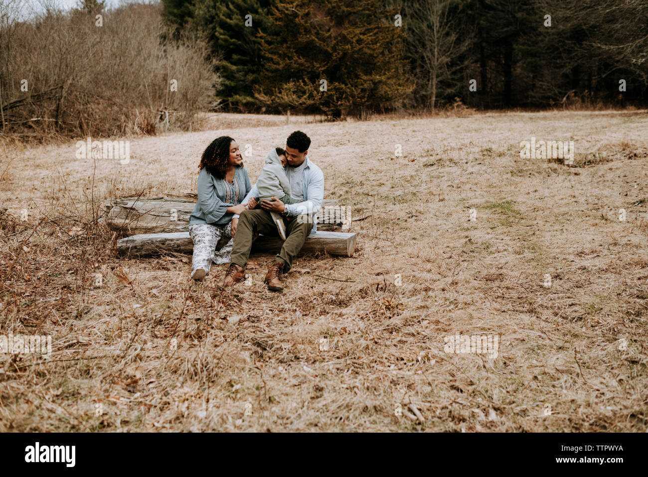 Couple talking while sitting avec fils sur log in forest Banque D'Images