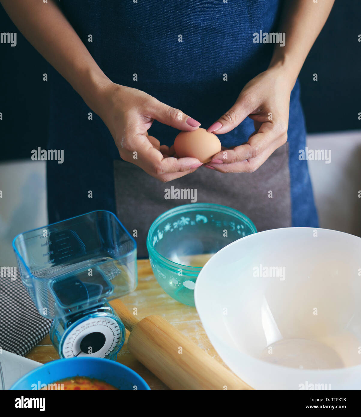 Midsection of woman breaking egg en cuisine à bol Banque D'Images