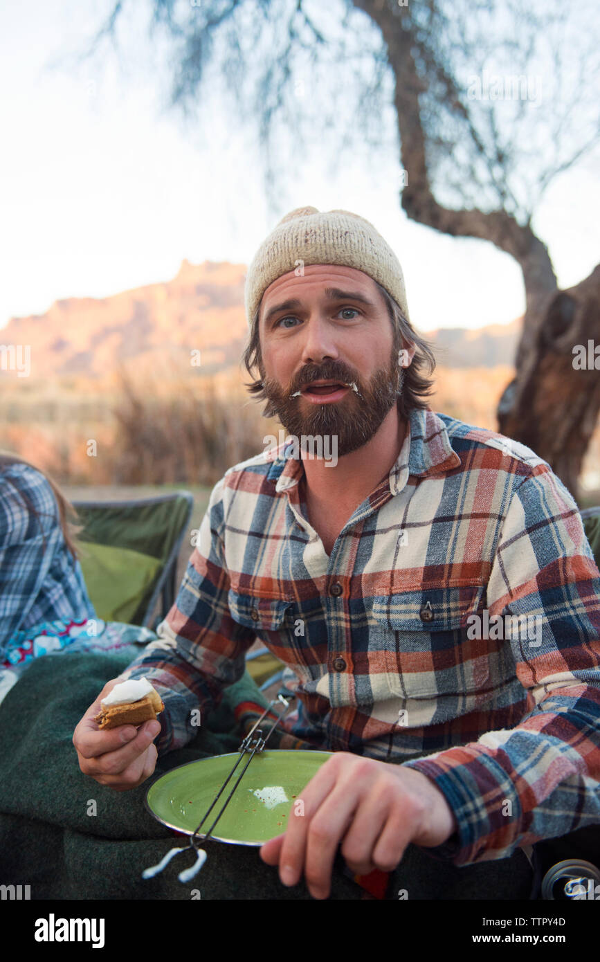 Portrait d'un homme avec la bouche malpropre holding s'more à camp site Banque D'Images