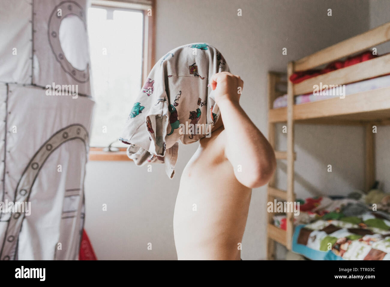 Vue latérale du garçon vêtus de t-shirt dans la chambre à la maison Banque D'Images