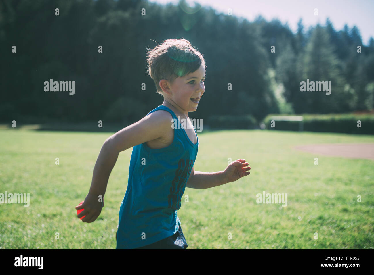 Vue latérale d'happy boy running with ball at park Banque D'Images