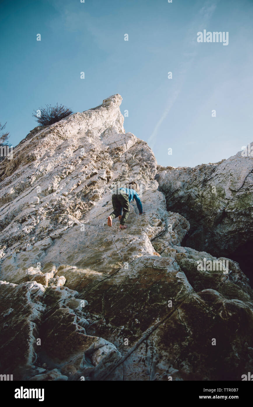 Low angle view of garçon insouciant de grimper sur des rochers Banque D'Images