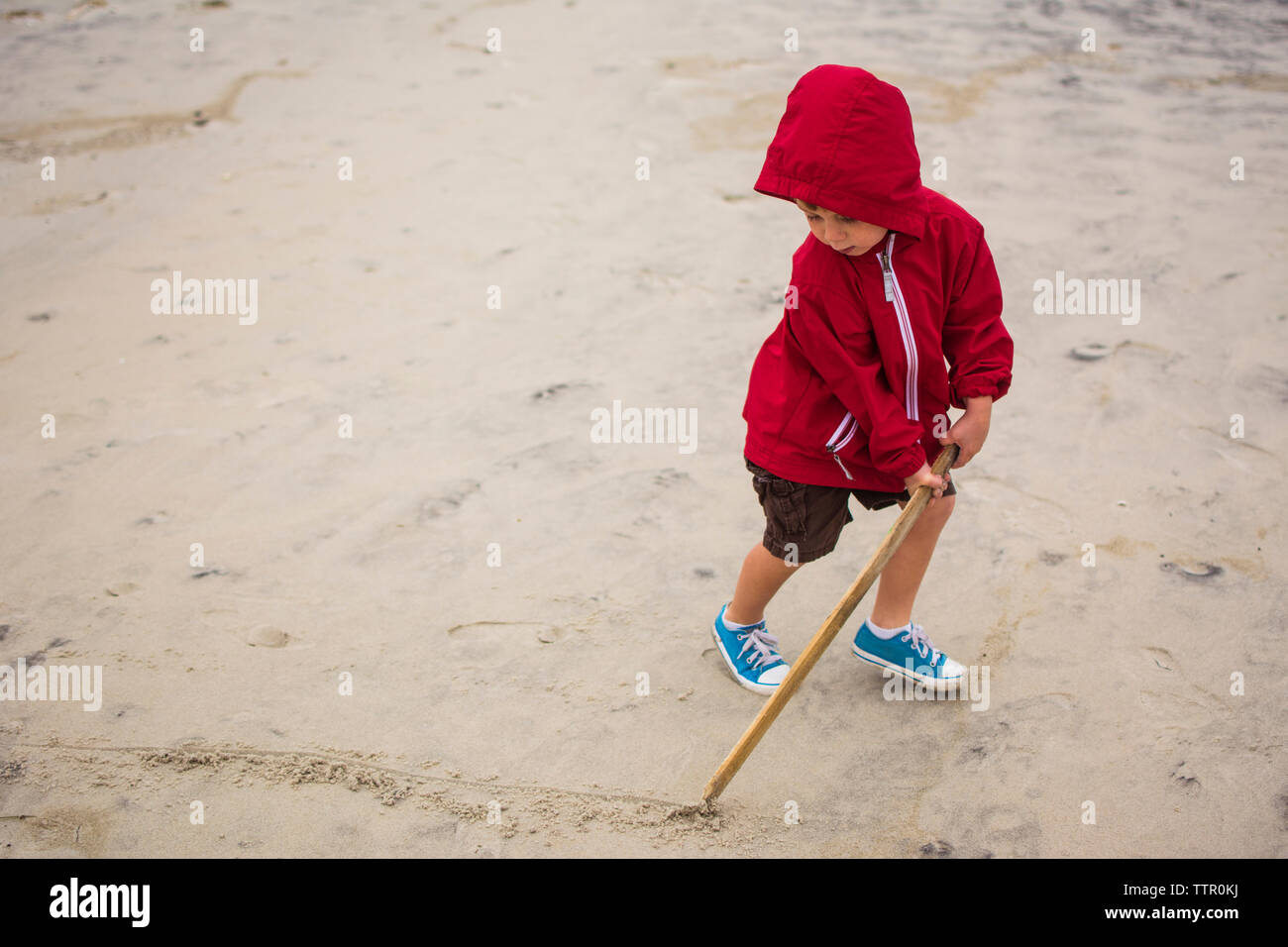 Portrait of boy drawing line sur sable avec stick Banque D'Images