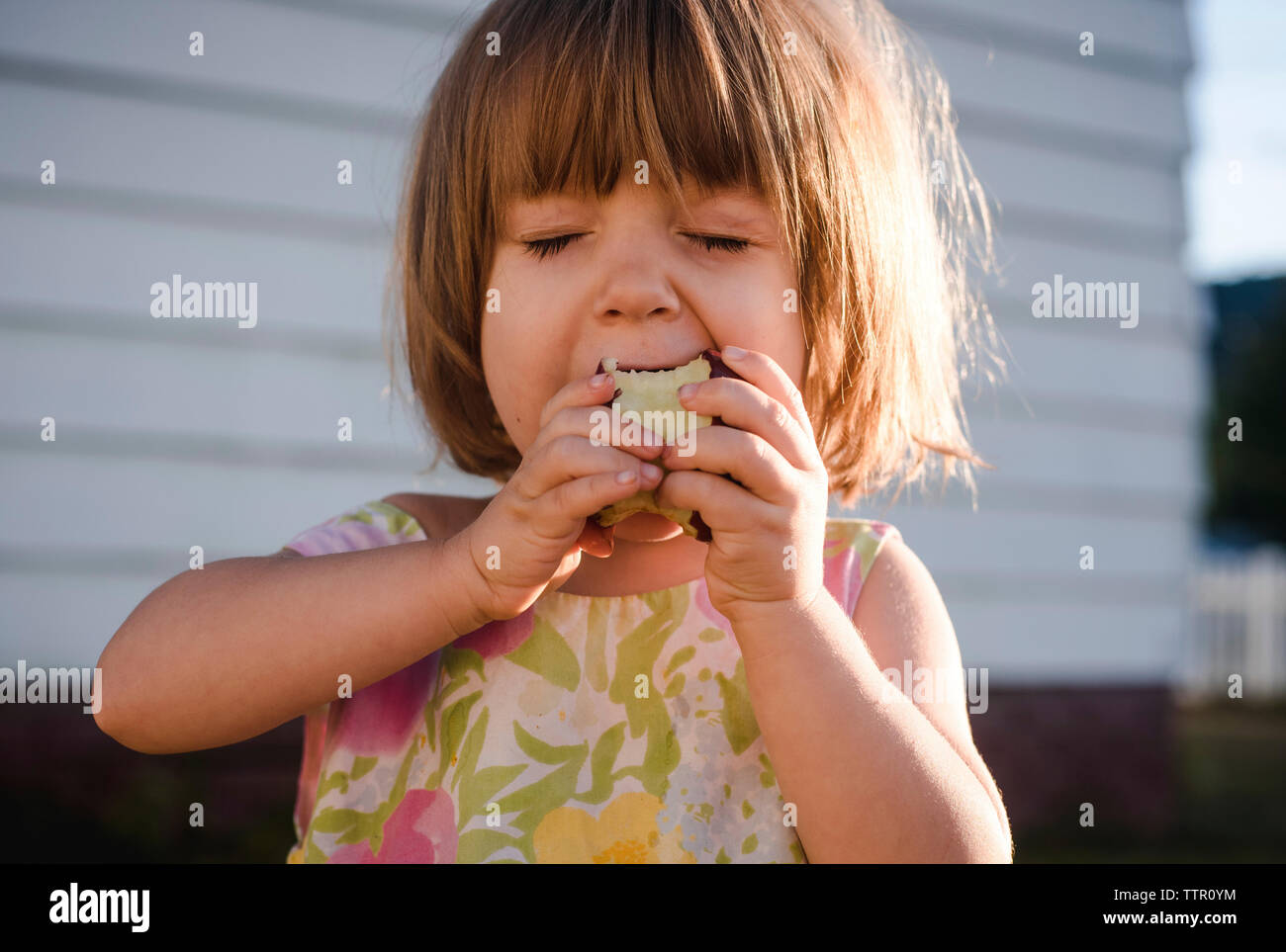 Close-up of girl eating apple en position debout contre le mur Banque D'Images