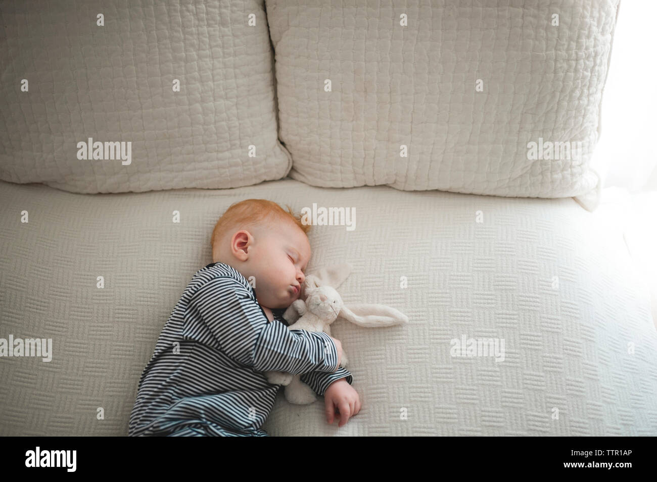 High angle view of cute baby boy dormir avec doudou on bed Banque D'Images