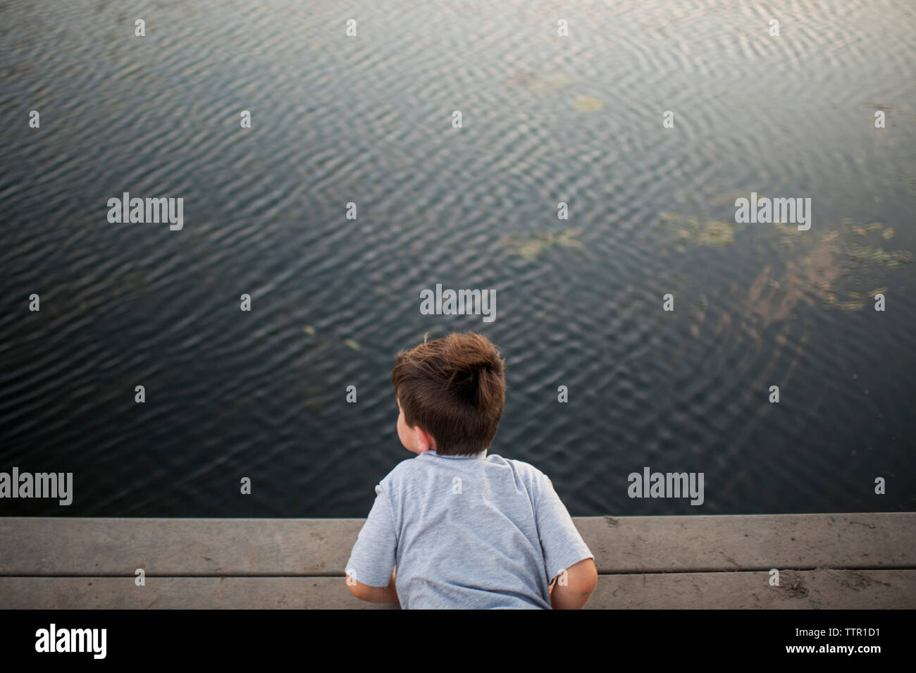 Portrait de garçon couché sur la jetée sur le lac at park Banque D'Images