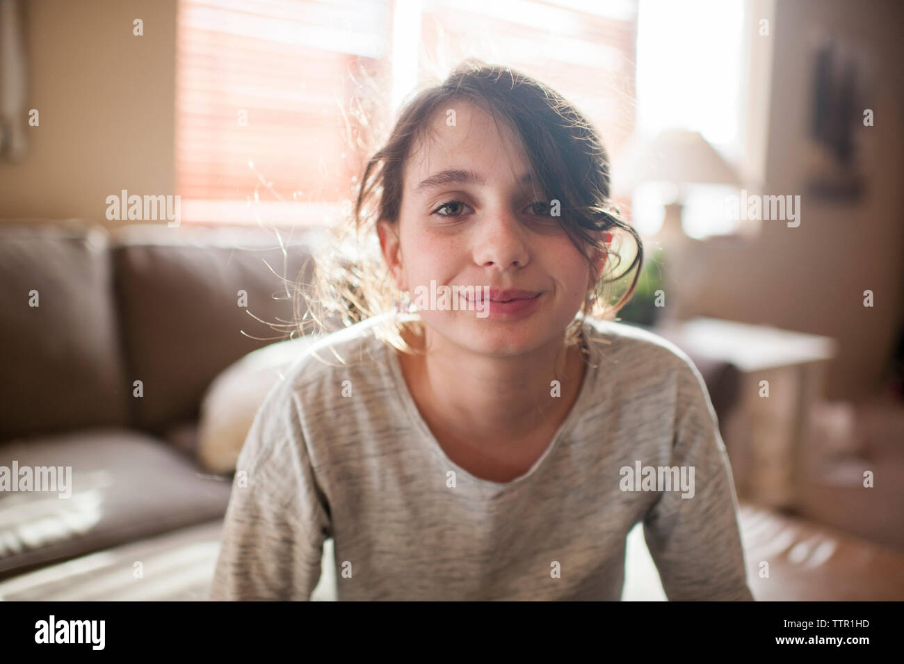 Portrait of smiling girl sitting at home Banque D'Images