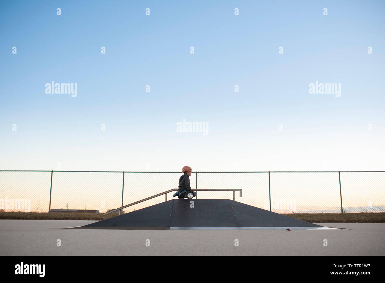 Jeune garçon sur le dessus de la rampe sur hover board à skate park contre le ciel bleu Banque D'Images