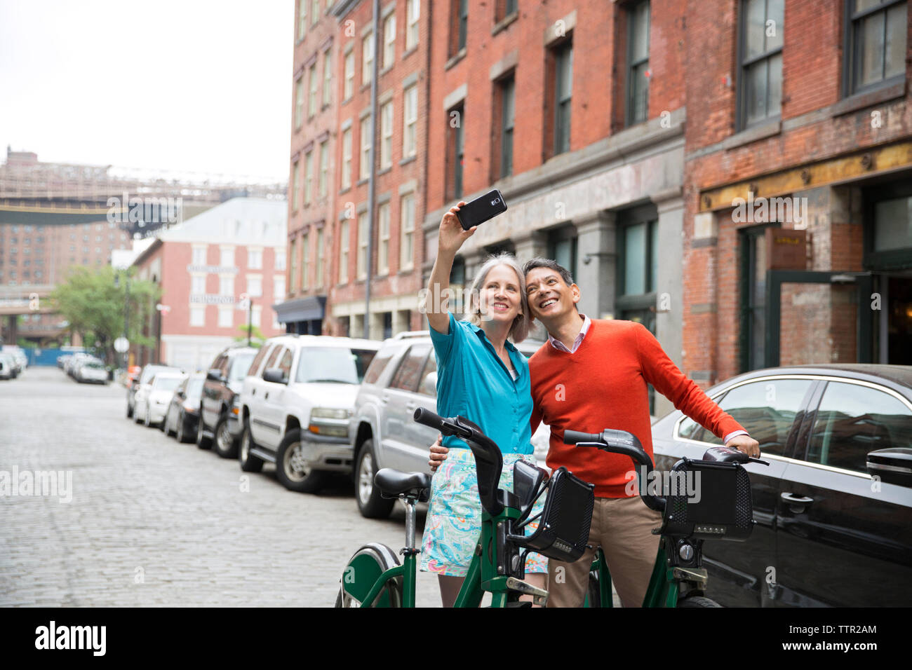 Couple en tenant debout selfies avec des vélos on city street Banque D'Images