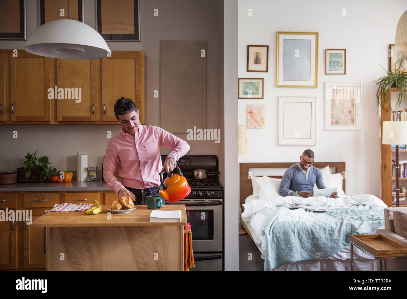 L'homme homosexuel pouring Coffee cup alors que dans l'aide de partenaire laptop at home Banque D'Images