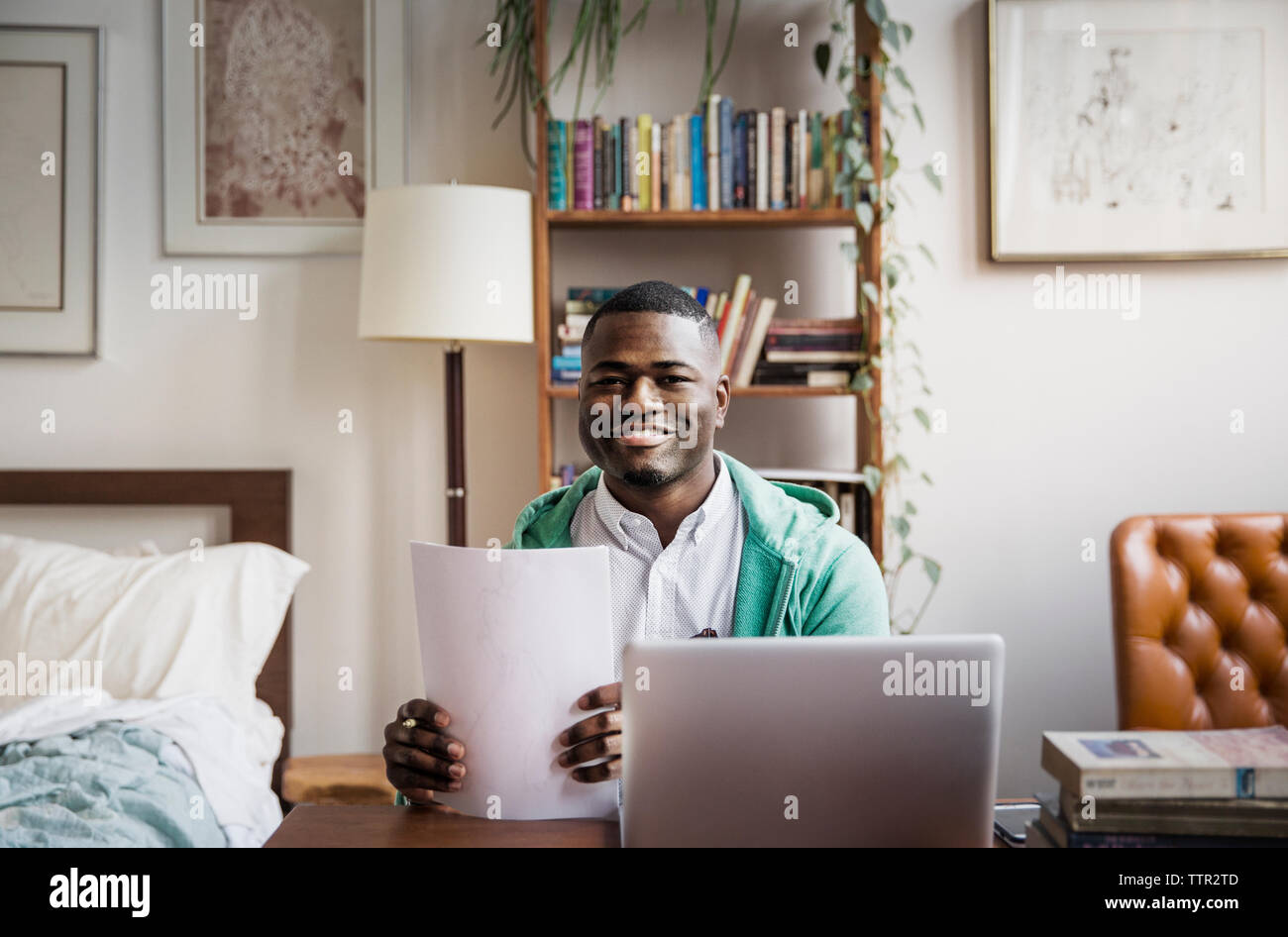 Portrait of happy man holding documents, tandis que le travail à domicile Banque D'Images