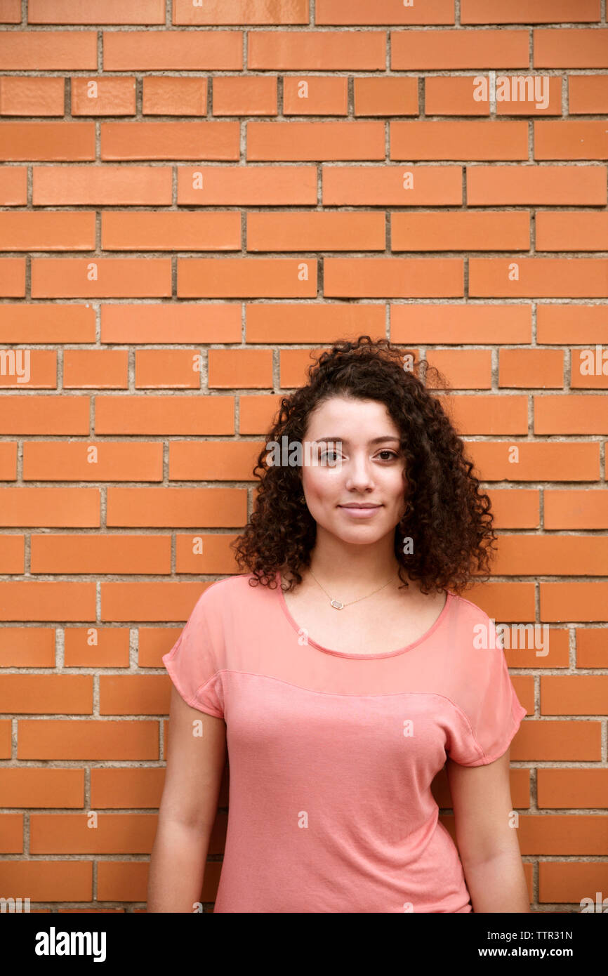Portrait of confident businesswoman standing against brick wall Banque D'Images