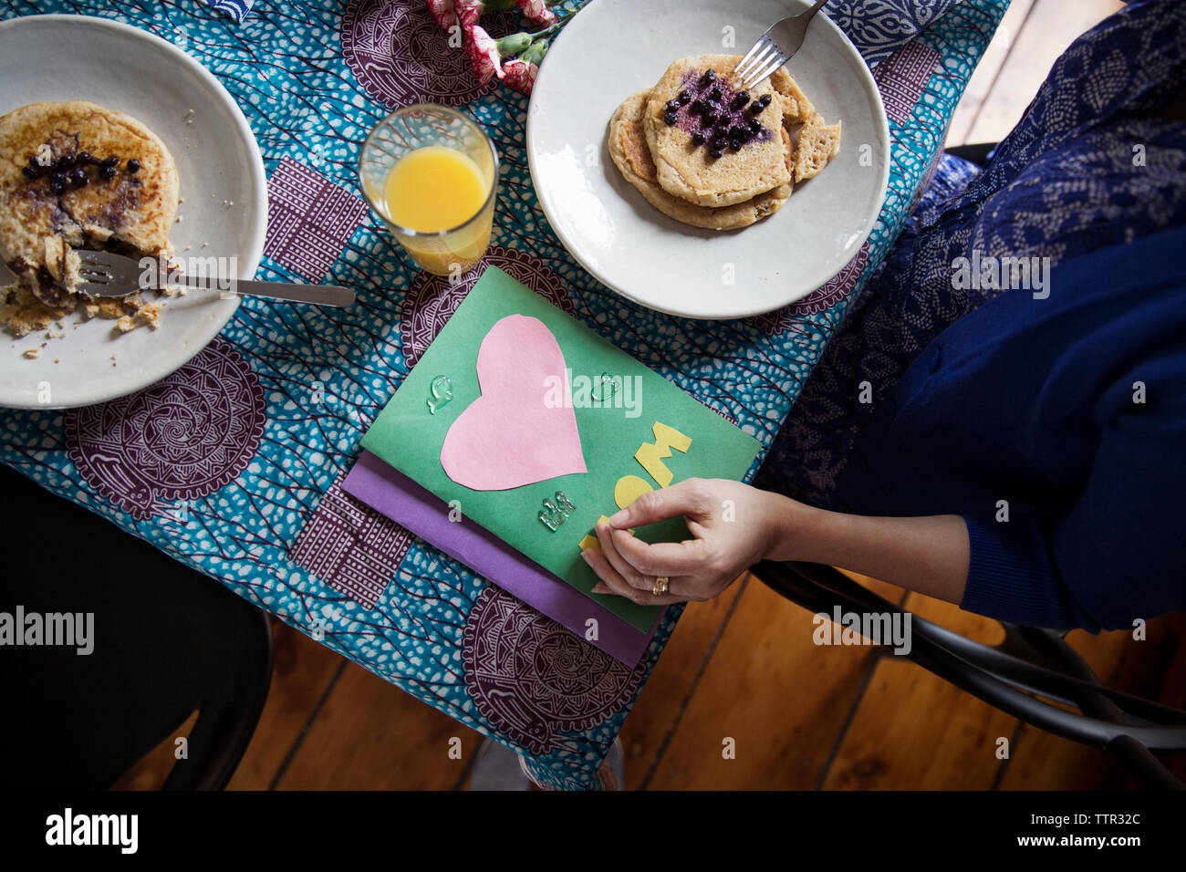Vue de dessus de woman eating pancakes par cartes de vœux sur table sur anniversaire Banque D'Images