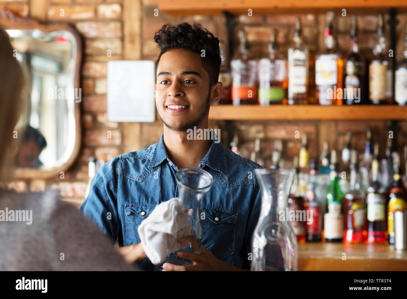 Propriétaire souriant lunettes nettoyage pendant la recherche de client au comptoir de cafe Banque D'Images