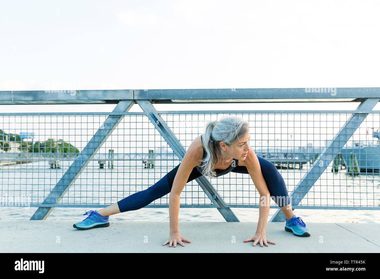 Femme de l'exercice sur le pont contre un ciel clair Banque D'Images