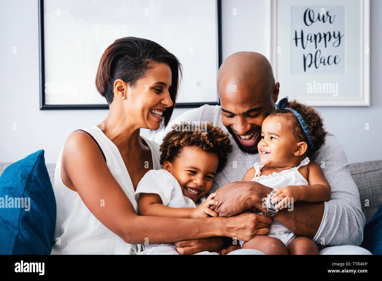 Heureux parents jouer avec les enfants mignons, assis sur un canapé à la maison Banque D'Images
