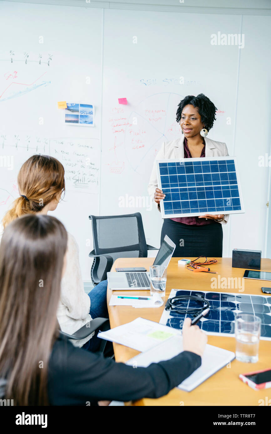 femme d'affaires expliquant le modèle de panneau solaire à des collègues féminins pendant la réunion Banque D'Images