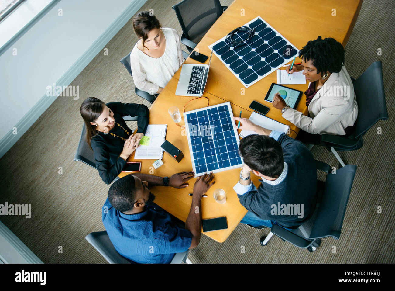 Vue aérienne de gens d'affaires de discuter sur des modèles de panneaux solaires au cours de réunion Banque D'Images
