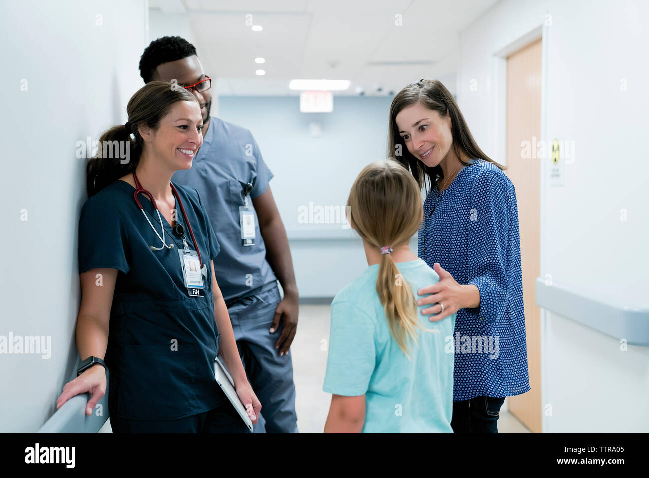 Les médecins à la surprise à parler avec mère fille in hospital corridor Banque D'Images