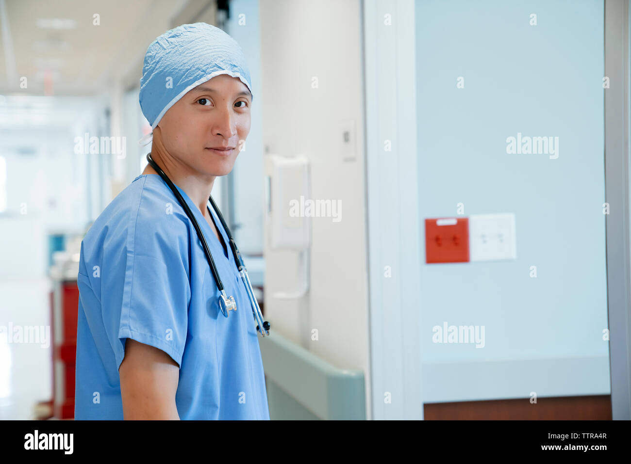 Portrait of smiling surgeon standing in hospital corridor Banque D'Images