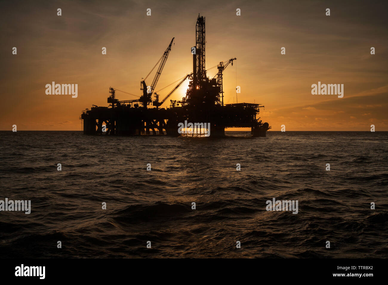 Plate-forme pétrolière en mer contre sky pendant le coucher du soleil Banque D'Images