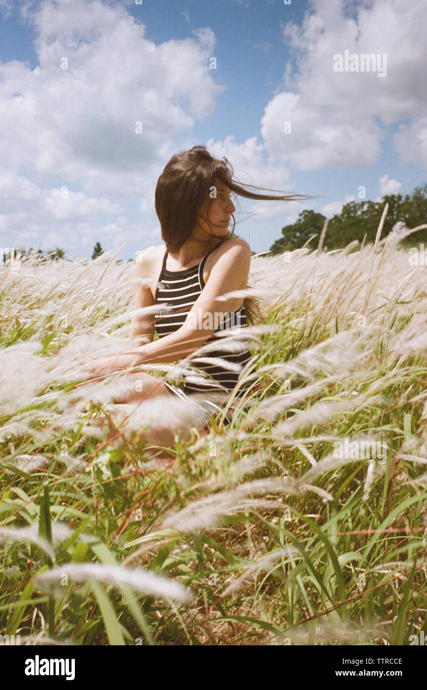 Femme assise sur le terrain contre ciel lors de vent Banque D'Images