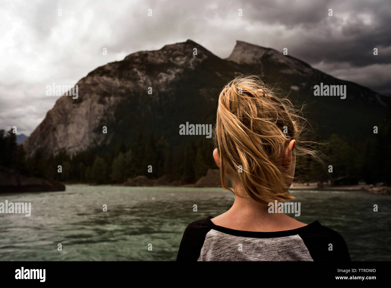 Vue arrière de fille avec des cheveux blonds debout près de lake against cloudy sky Banque D'Images