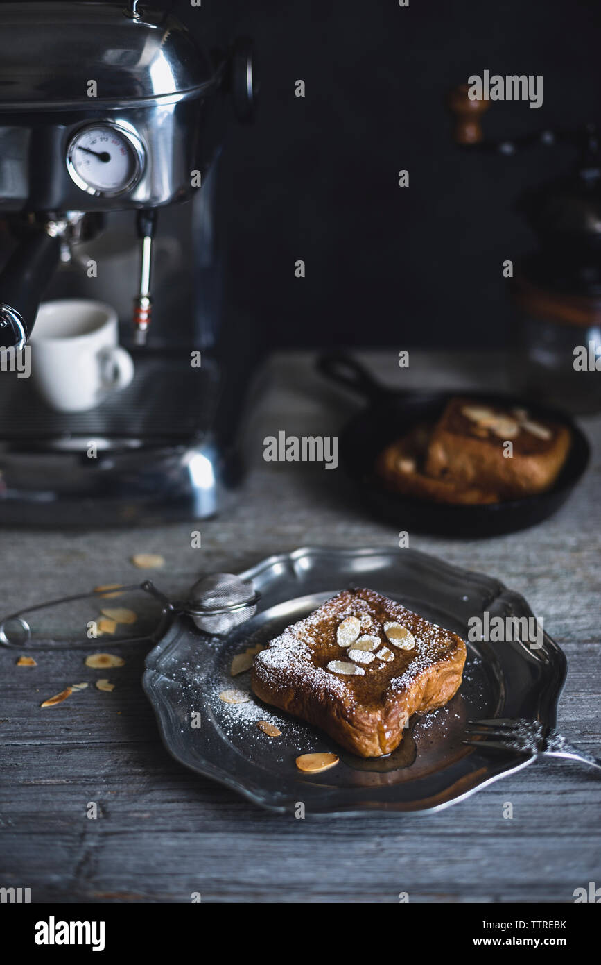 Toasts à la française avec amandes servi dans la plaque par machine à expresso sur table en bois Banque D'Images