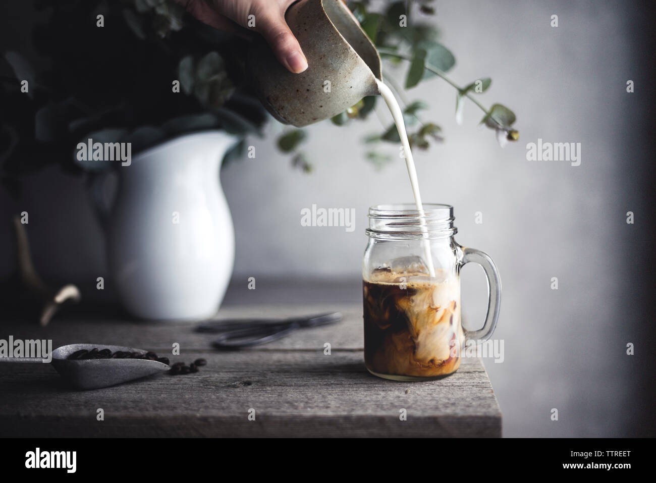 Portrait of woman pouring milk dans le café Banque D'Images