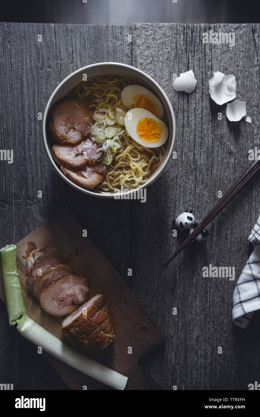 Vue supérieure de l'omble chevalier et de porc sui nouilles ramen avec oeuf sur table en bois Banque D'Images
