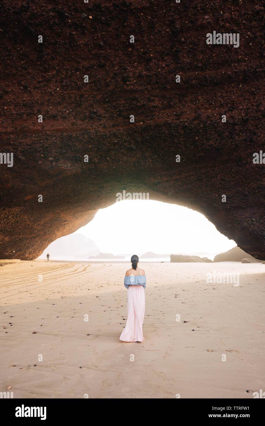 Vue arrière de la femme debout à la plage par mountain Banque D'Images