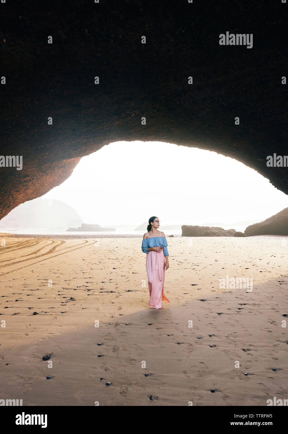 Femme debout à la plage par mountain Banque D'Images