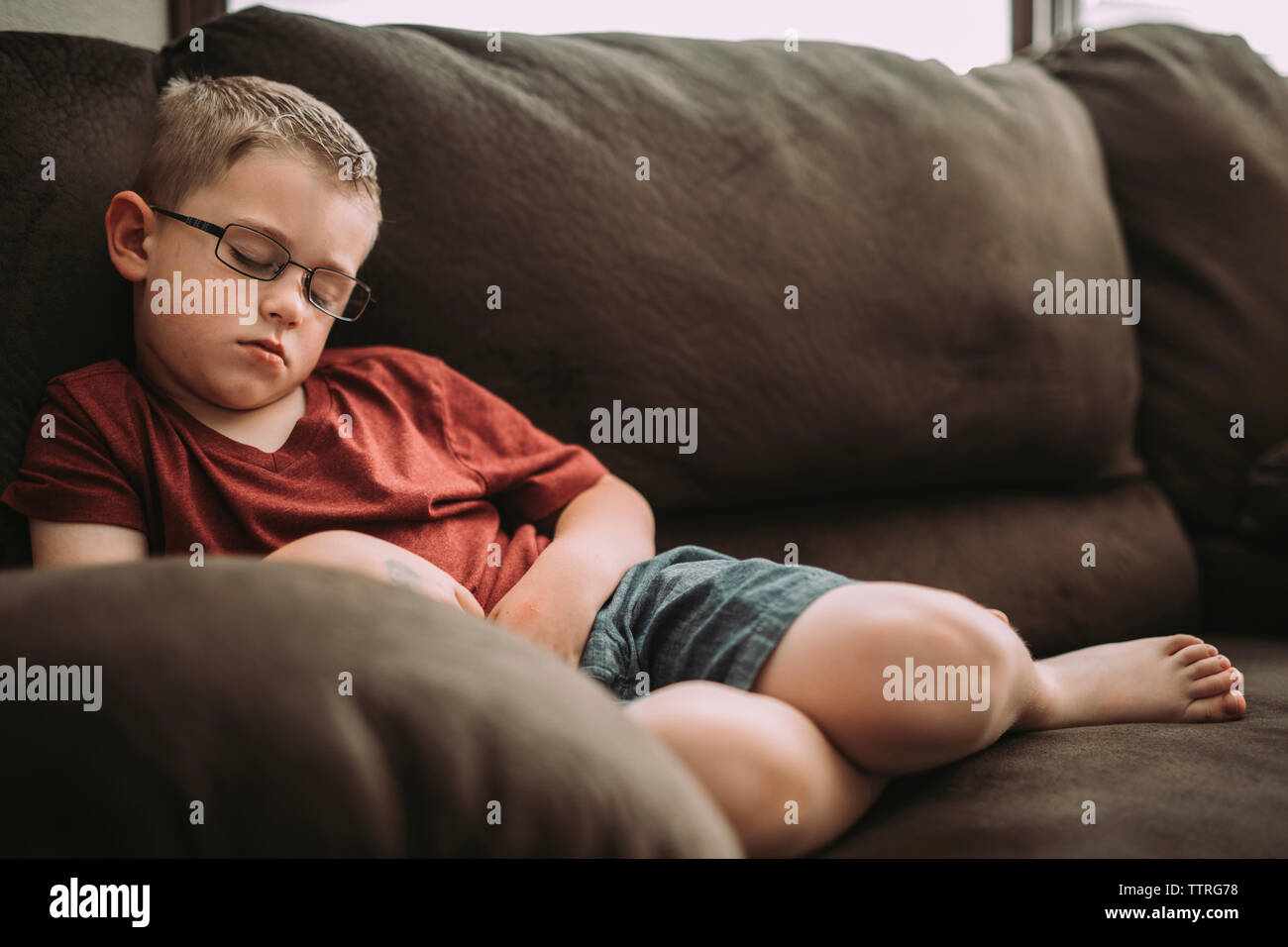 Le garçon endormi sur le canapé à la maison Banque D'Images