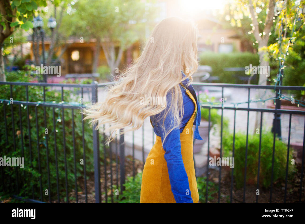 Femme aux cheveux blonds autour d'une clôture au parc sur sunny day Banque D'Images