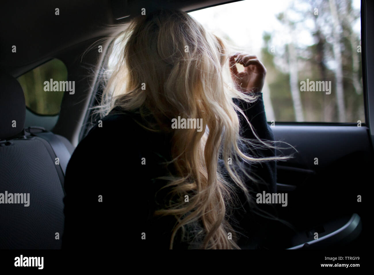 Adolescent avec des cheveux longs à la fenêtre en voiture en Banque D'Images