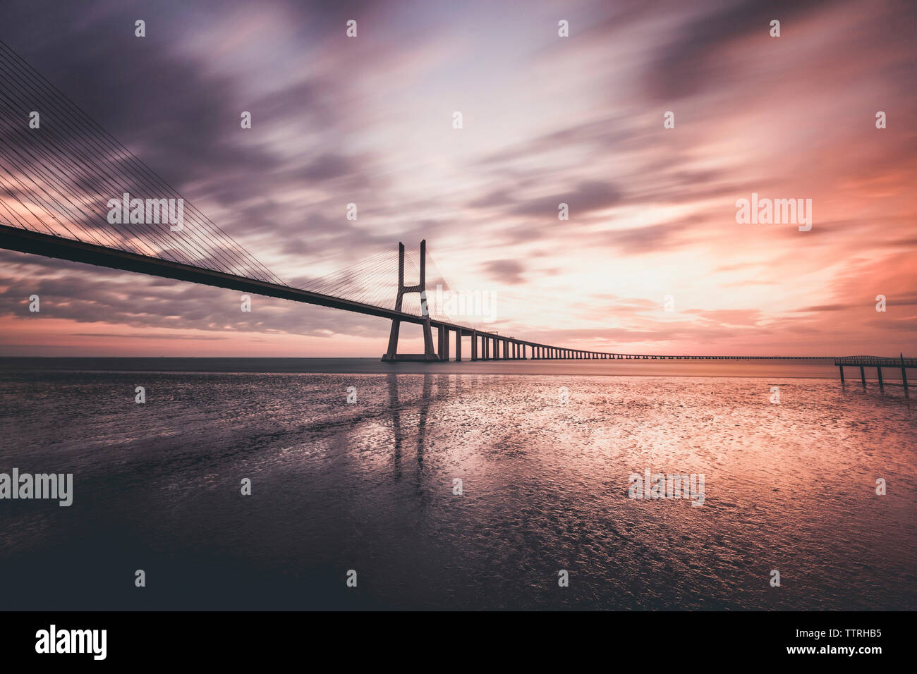 Silhouette Pont Vasco da Gama sur le fleuve Tage contre ciel nuageux au lever du soleil Banque D'Images