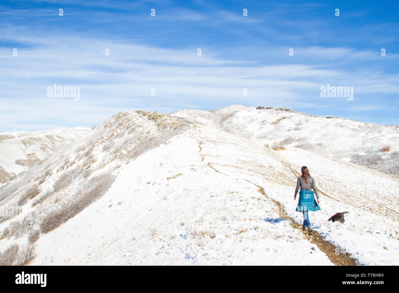 Vue arrière du woman walking on mountain contre ciel nuageux au cours de l'hiver Banque D'Images