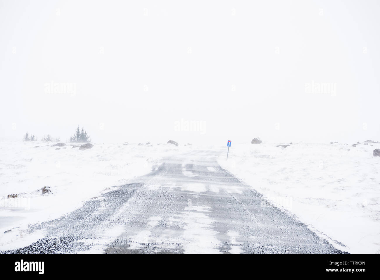 Au milieu de la route couverte de neige contre champ ciel clair Banque D'Images