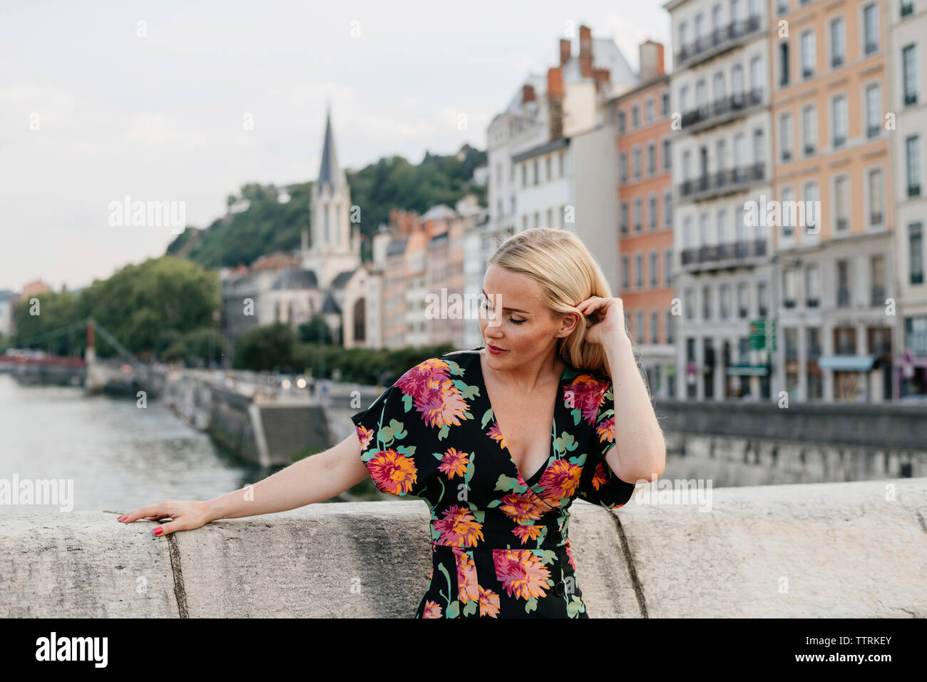 Femme debout sur la passerelle sur la rivière contre les bâtiments en ville Banque D'Images