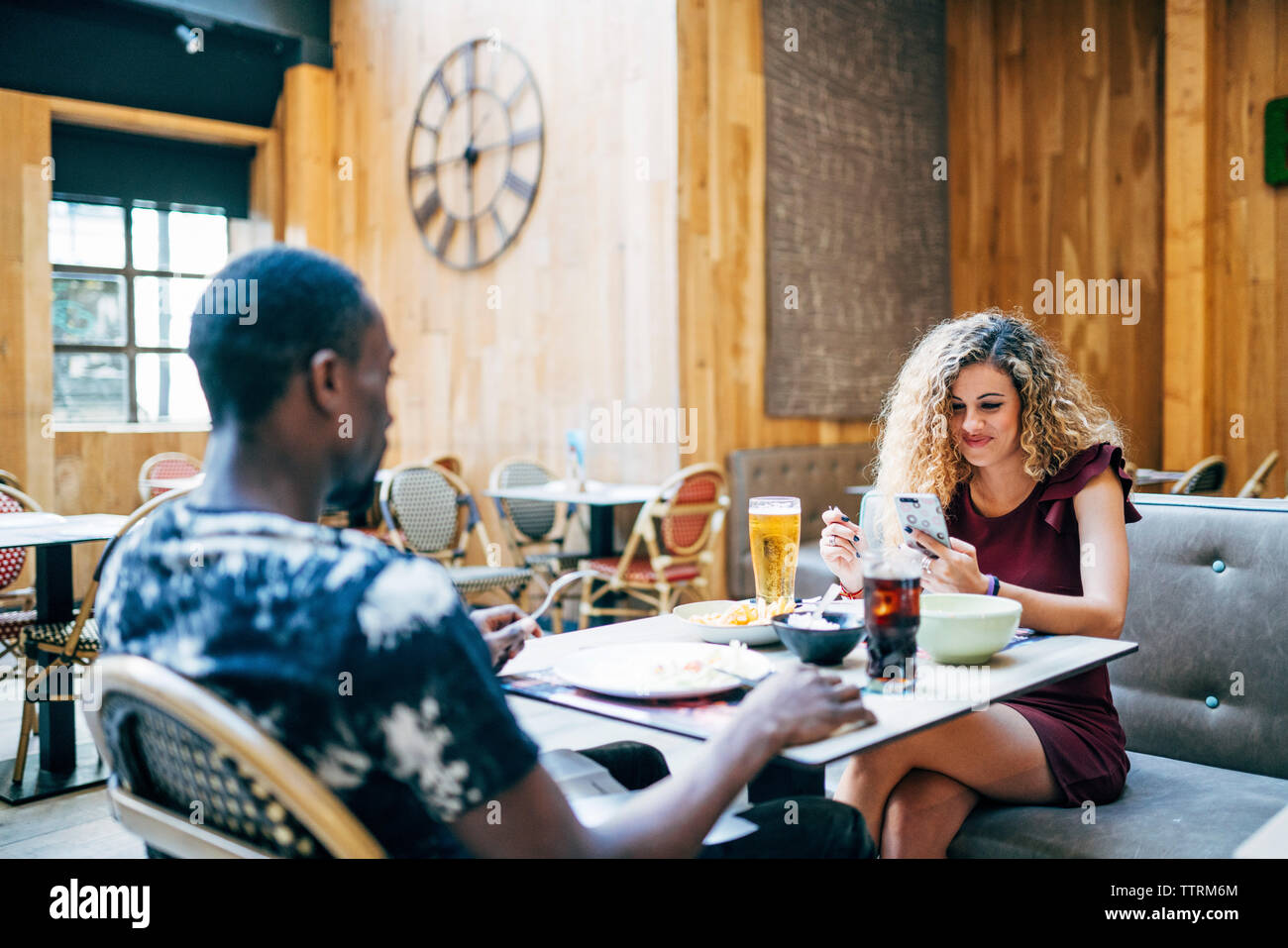 Femme blonde et l'homme africain aiment manger au restaurant. Banque D'Images