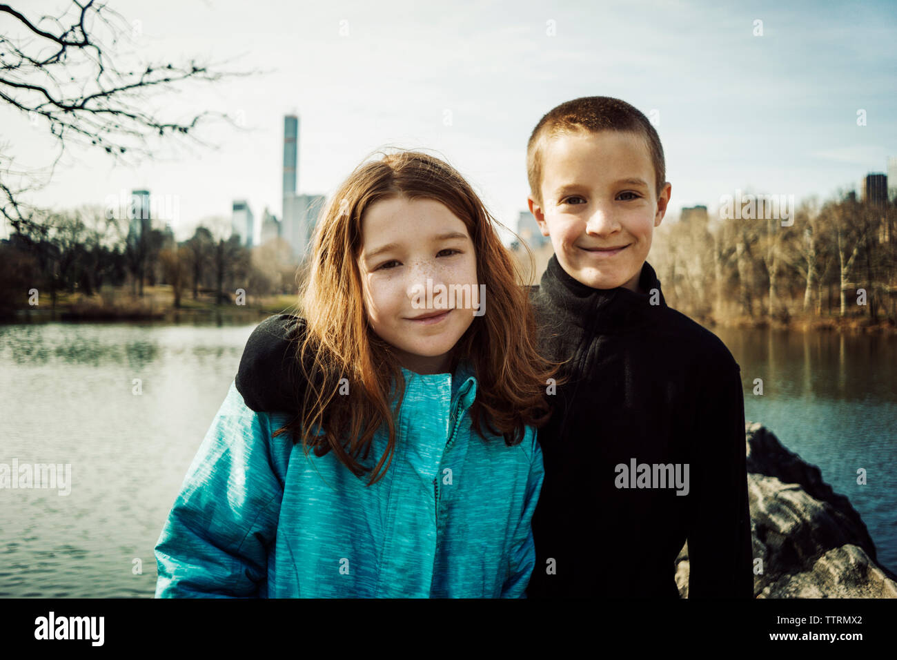 Portrait of smiling brother avec bras autour de sœur à lake in park Banque D'Images