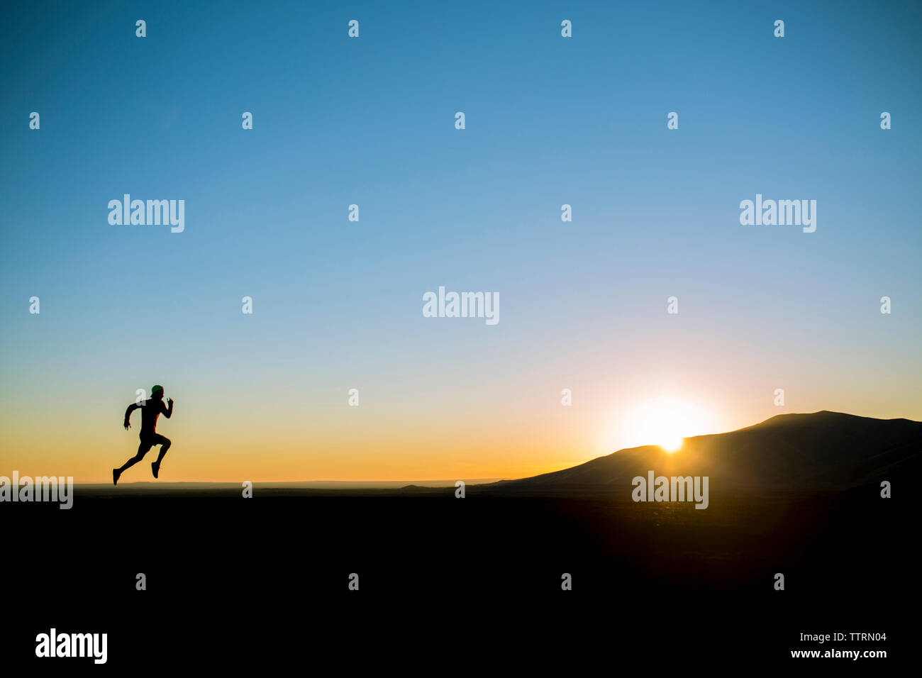 Silhouette homme court sur terrain contre ciel bleu clair Banque D'Images