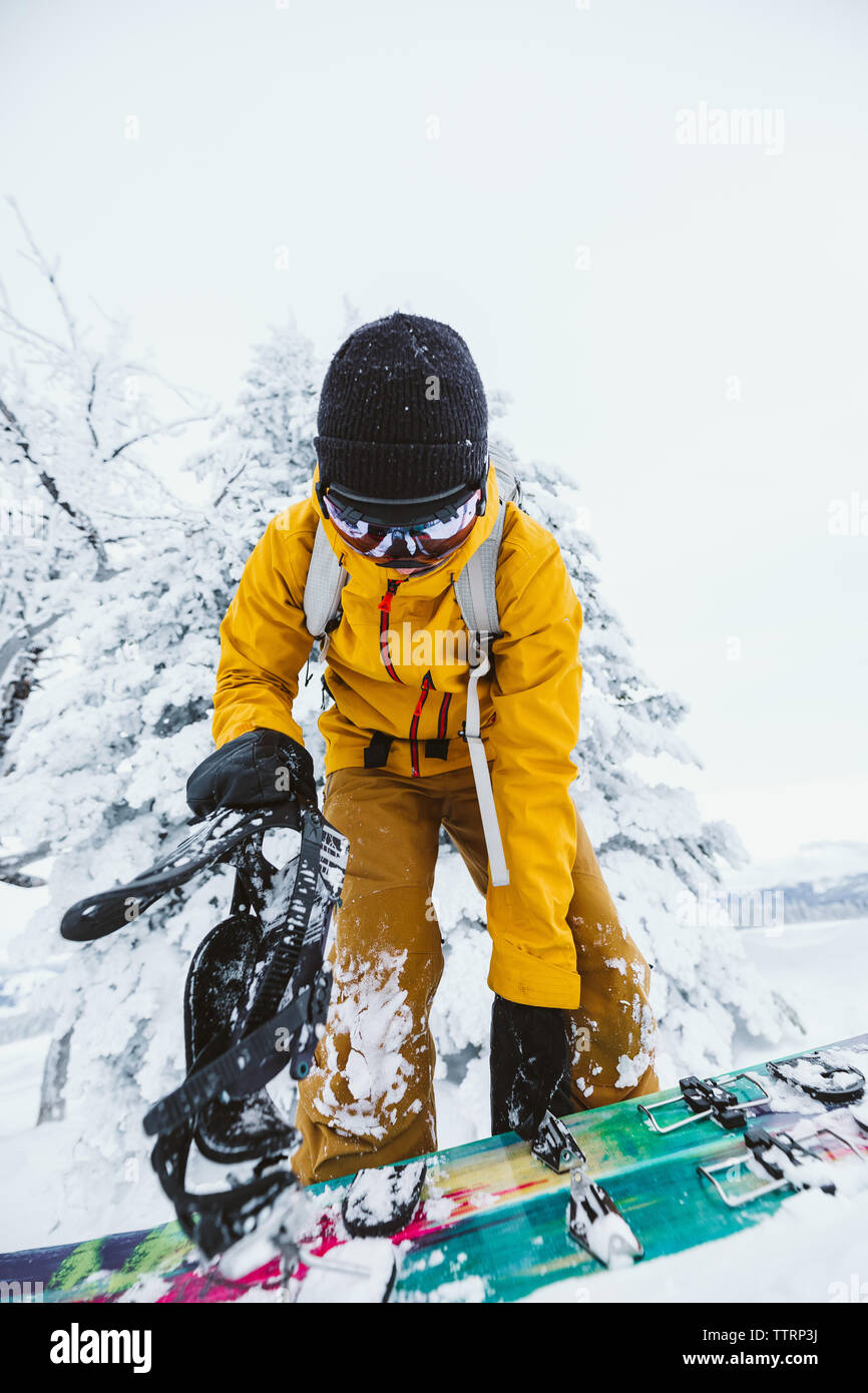 Snowboarder dans yellow jacket s'apprête à déchiqueter dans le Wyoming l'hiver Banque D'Images