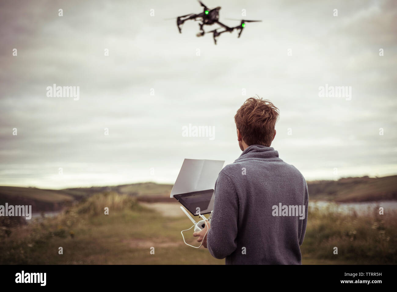 Vue arrière de l'exploitation de l'homme appareil photo drone en se tenant sur le terrain Banque D'Images