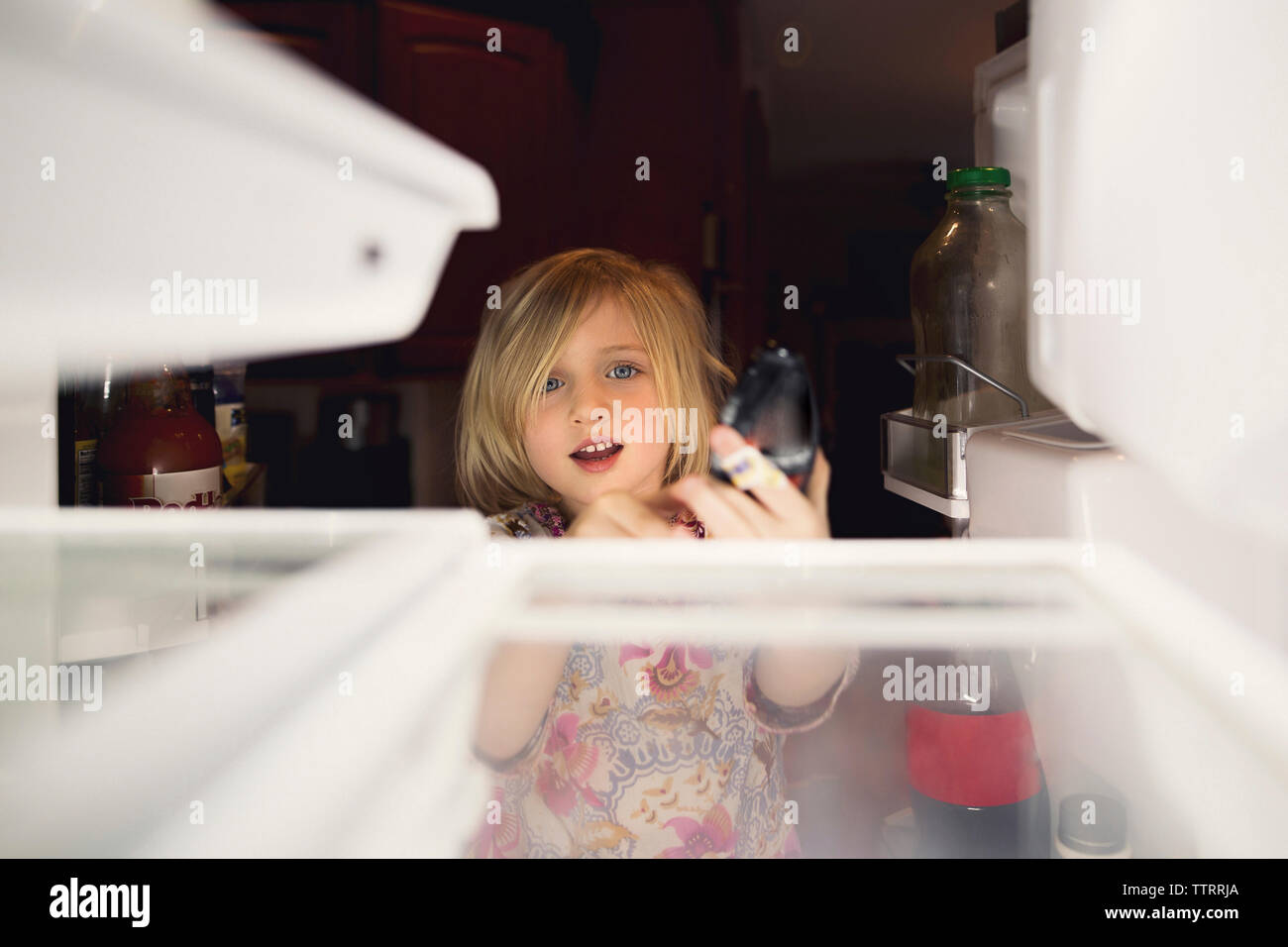 Jolie fille à la recherche en réfrigérateur à la maison Banque D'Images