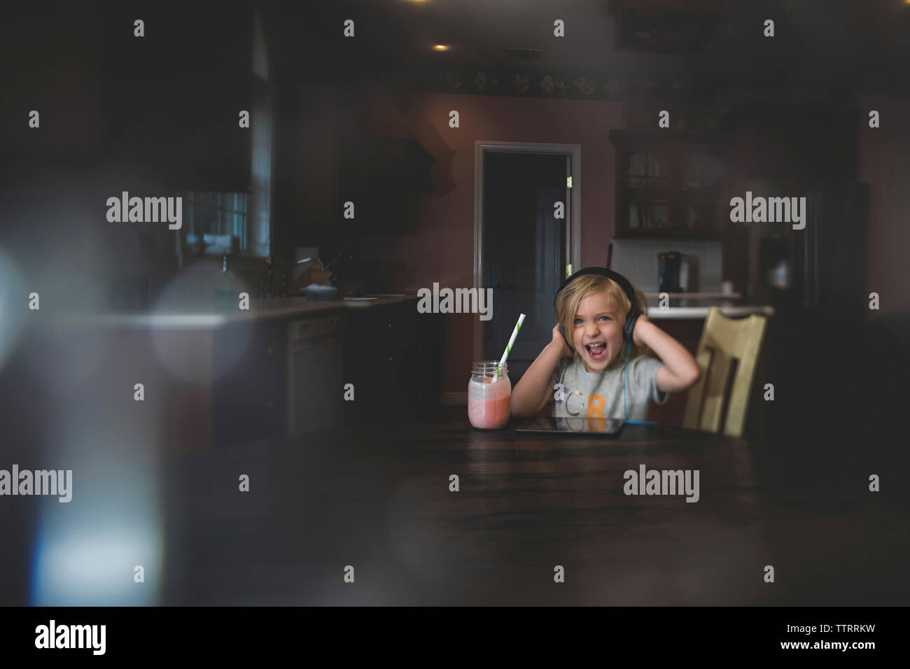 Cheerful girl listening music par ordinateur tablette tout en ayant frappé à table Banque D'Images