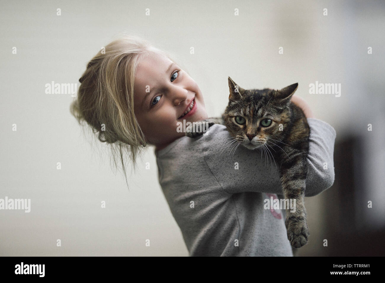 Portrait of cute girl holding cat à la maison Banque D'Images