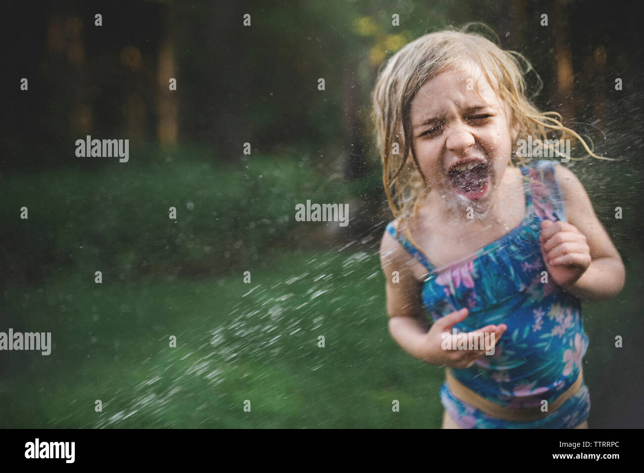 Girl enjoying dans l'eau pulvérisée à l'arrière-cour Banque D'Images