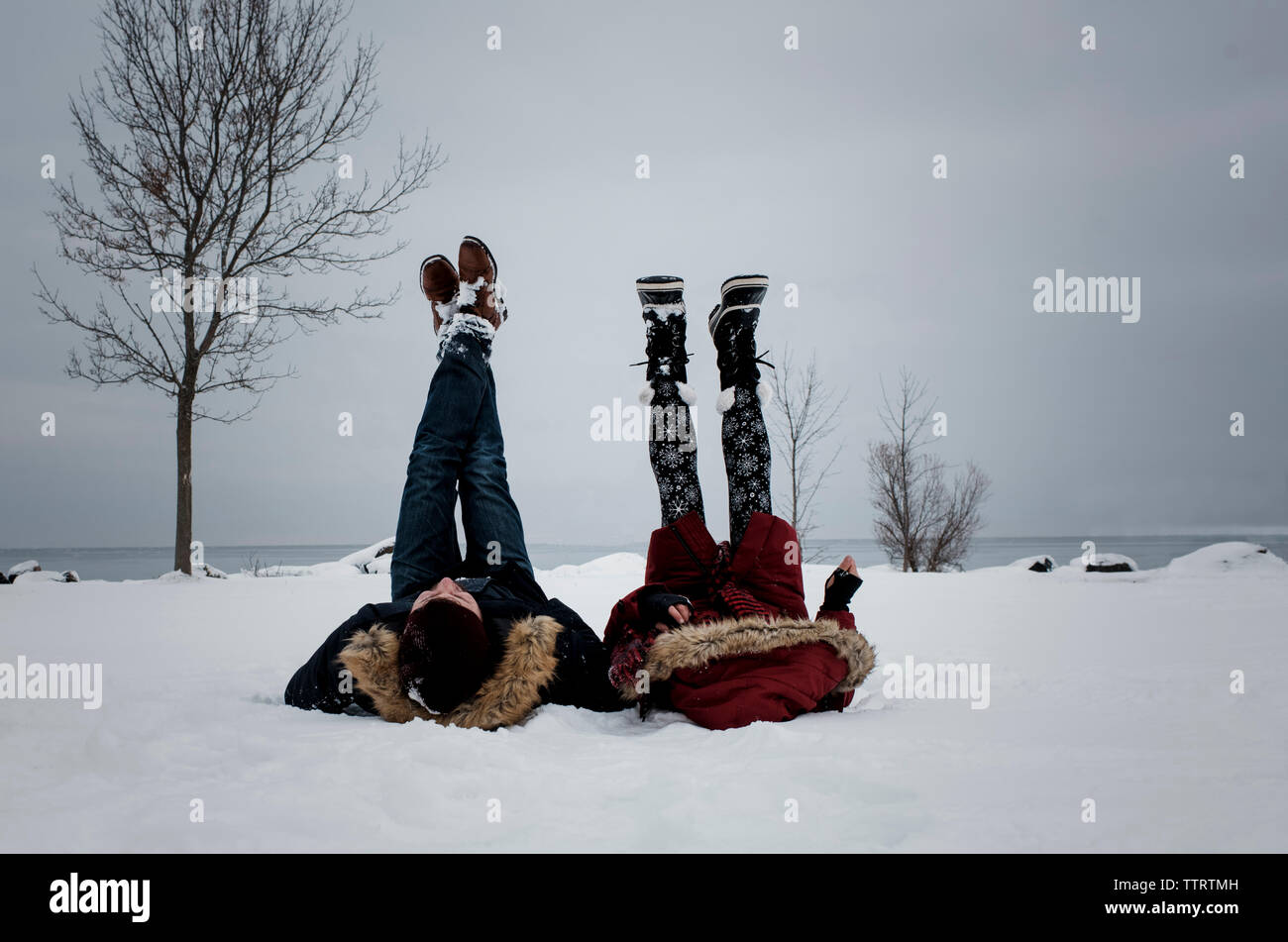 Les amis de la plage couverte de neige pendant l'hiver contre le ciel Banque D'Images